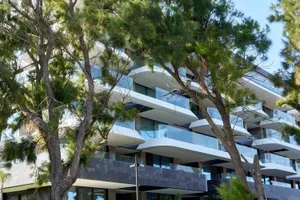 Modern residential exterior featuring large glass balconies and stone accents