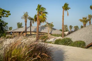 A modern house with wooden exterior surrounded by grass and sand