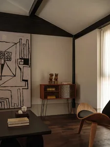A modern living room with concrete walls, a wooden table, and a glass cabinet.