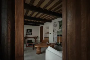 A modern living room with wooden furniture, leather accents, and concrete flooring.