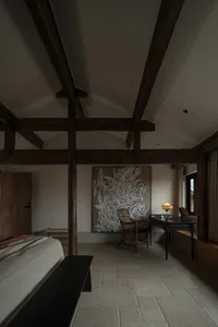 A modern minimalist bedroom featuring a floating bed, exposed wooden beams, and a large abstract painting.