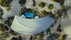 An aerial view of a modern residential structure with a curved roof and tiled materials.
