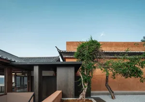 A modern building with a terracotta exterior and a tree in the foreground.