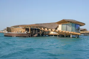 Modern, minimalist waterfront resort buildings floating on the ocean.