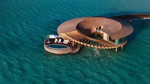Round floating resort structure with a wooden deck and pool over the ocean