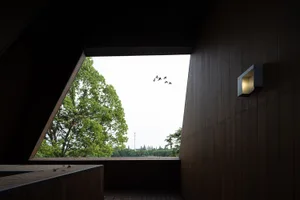 A modern interior showcasing wooden walls and a triangular architectural window.