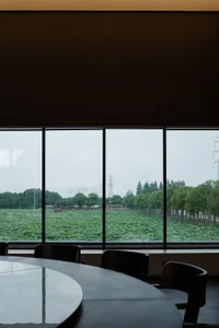 Restaurant interior featuring a large glass window overlooking green foliage.