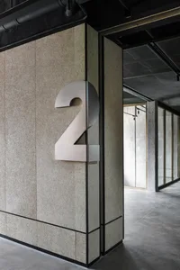A modern building number sign made of metal attached to a wall.