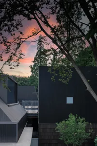 Modern exterior featuring sleek, black metal-clad panels under a dramatic, sunset sky.