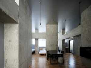 A photograph showcasing a modern industrial residential interior with concrete walls and wooden parquet flooring.