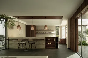A modern living room featuring a bar area with sandstone and walnut finishes.