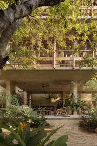 A modern lobby with concrete walls and a high ceiling, featuring a large seating area and a large window.