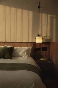 A modern minimalist bedroom with a white bed, wooden walls, and textured fabric bedding.