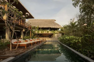 Modern residential swimming pool area with concrete decking and wooden structures.