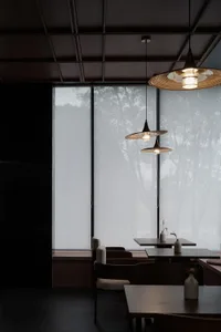 A modern restaurant interior featuring glass walls and minimalistic design elements.
