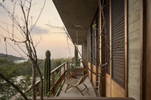 Teak wood balcony featuring a wicker chair and potted plants with a scenic ocean view.