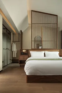 A minimalist bedroom featuring a wooden bed with white bedding and a bamboo partition.