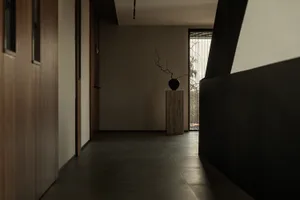 A minimalist corridor interior with a simple vase and branch arrangement on a pedestal, featuring clean lines and a neutral c