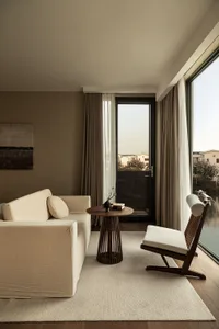A minimalist living room featuring a neutral-tone palette, natural lighting, and comfortable seating.