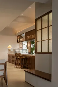 Modern coffee shop featuring a sleek, dark wood bar counter with glass windows and steel accents.