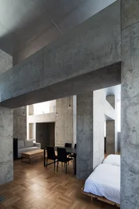 Modern minimalist living space featuring concrete walls and wood flooring.