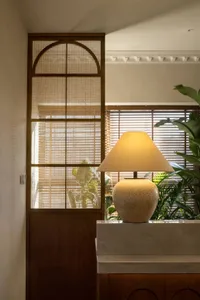 A ceramic lamp with a conical shade illuminates a space, adding a warm glow.