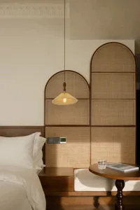 A minimalist bedroom featuring wood elements and a hanging light fixture.
