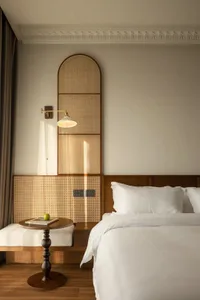 Minimalist bedroom with woven wood accents and white bedding.