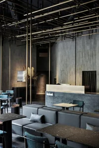 Industrial-style bar area with concrete walls, metal lighting fixtures, and leather seating.