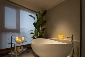 Modern bathroom featuring candles and a plant.
