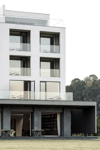 Modern building with concrete and glass exterior, featuring balconies and large windows.