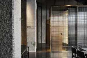 A minimalist restaurant interior with metal, glass, and concrete finishes, featuring a modern design aesthetic.