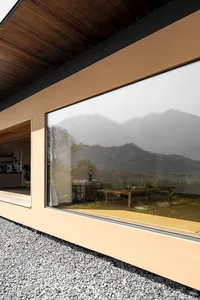 A minimalist residential interior with large glass windows showing a view of mountains.