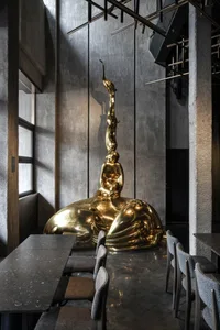 A modern restaurant interior showcasing a large, metallic sculpture in the center of the room.