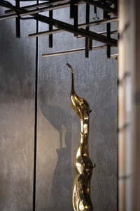 A brass sculpture depicting a draped female figure with an elongated neck and flowing form.