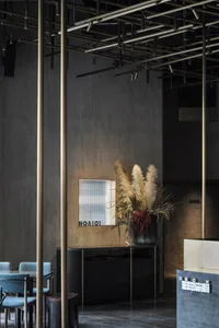 Concrete walls, industrial lighting, and minimalist decor of a restaurant interior