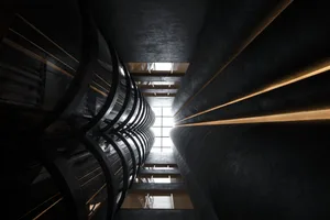 A black metallic staircase with curved railings inside a building with high ceilings and natural light.