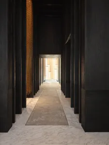A modern hotel corridor with marble flooring and black wooden walls