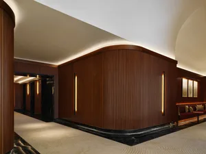 A modern lobby featuring dark wooden walls with vertical ribbing and recessed lighting. The room has a sleek, contemporary de