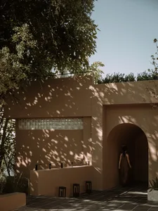 A minimalist entryway with concrete walls and shadows from surrounding trees.
