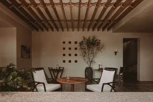 A minimalist interior space featuring wooden furniture and a wooden ceiling with exposed beams.