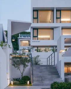 Modern building with concrete and glass exterior, metal railings and greenery.