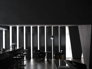 A modern, minimalist restaurant bar lounge with metallic furniture and dark lighting.