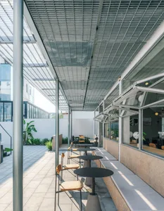 Modern industrial-style cafe with concrete beams and seating areas.