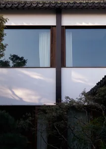 A modern exterior wall with large windows and white curtains.