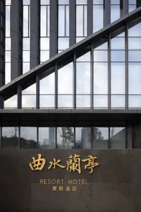 Modern glass facade of a hotel with large windows and a sign that reads 'RESORT HOTEL'.