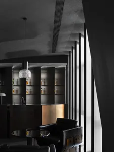 A modern hotel suite bar featuring black walls, metal accents, and a large window.