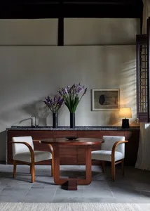 Modern living room featuring two upholstered chairs, a wooden table with a bowl, and a black marble countertop with purple fl