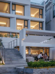 Modern residential exterior features concrete stairs, glass windows, and illuminated interior.