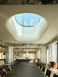 A modern restaurant interior with marble walls and a large skylight.